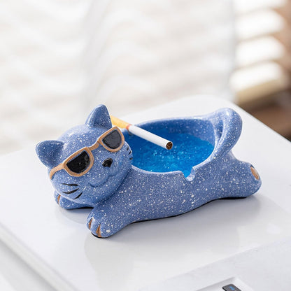 Bittchaser Supply Co. blue speckled ceramic Lucky Cat ashtray with sunglasses on a white tabletop.