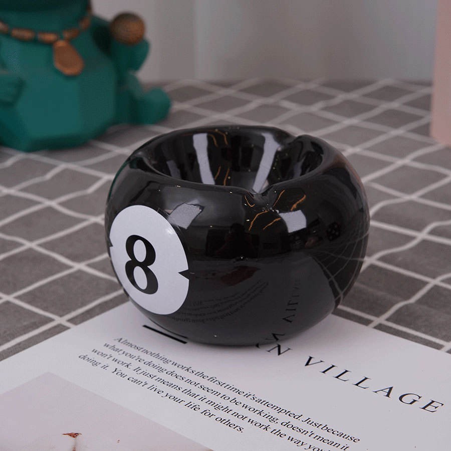 Bittchaser Supply Co. black ceramic 8 ball billiard ashtray with a glossy glazed finish on a tabletop.